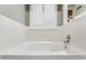 White bathtub and shower, tiled surround and a bright window with shutters at 19127 N 79Th Dr, Glendale, AZ 85308