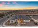 Aerial view showcases luxury home with landscape lighting, a three-car garage, and gorgeous sunset colors at 20426 E Arroyo Verde Dr, Queen Creek, AZ 85142