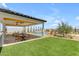 A covered outdoor kitchen overlooks a pool, green lawn, and desert landscaping at 20426 E Arroyo Verde Dr, Queen Creek, AZ 85142