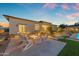 Inviting backyard featuring a cozy fire pit with chairs, lush greenery, and travertine pavers, perfect for outdoor relaxation at 20426 E Arroyo Verde Dr, Queen Creek, AZ 85142
