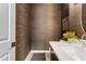 Stylish powder room with wood-look wallpaper and modern white vanity and sink at 20426 E Arroyo Verde Dr, Queen Creek, AZ 85142
