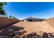 Flat, large backyard with low brick wall around the perimeter and clear blue sky at 21348 N Belt Dr, Maricopa, AZ 85138