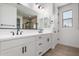 Bathroom with double vanity, white cabinets, and a large mirror with modern lighting at 21348 N Belt Dr, Maricopa, AZ 85138