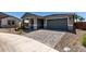 Gray single-Gathering home featuring a brick driveway, desert landscaping, and an attached garage at 21348 N Belt Dr, Maricopa, AZ 85138