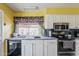 Well-lit kitchen has white cabinets and black appliances, offering a functional cooking space at 2202 W Enid Ave, Mesa, AZ 85202