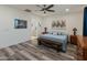 Spacious main bedroom with a wood accent bench, warm-toned wood furniture, a ceiling fan and an ensuite bathroom at 24638 N 144Th Ave, Surprise, AZ 85387