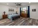 Cozy main bedroom featuring wood-look floors, a ceiling fan, and ample natural light from the large window at 24638 N 144Th Ave, Surprise, AZ 85387