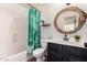 Bathroom with a tub and shower, black vanity, and modern round mirror at 33828 N Pate Pl, Cave Creek, AZ 85331