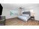 A spacious bedroom features wood floors, a large window, ceiling fan, and a gray upholstered king bed at 3813 W Lapenna Dr, New River, AZ 85087