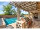 Outdoor kitchen and dining area are showcased next to the pool and covered patio in this backyard at 3813 W Lapenna Dr, New River, AZ 85087