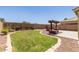 Lush backyard with green grass, a stone-lined edge, and a charming pergola seating area at 3929 W Goldmine Mountain Dr, San Tan Valley, AZ 85144