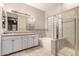 Bathroom featuring dual sinks, framed mirror, combined tub/shower with a glass enclosure at 4565 N Point Ridge Rd, Buckeye, AZ 85396