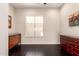 Empty room boasts lustrous wood floors, bright window, ceiling fan, and decorative furniture at 4565 N Point Ridge Rd, Buckeye, AZ 85396