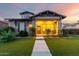Charming home exterior with a covered porch, stone accents, and lush landscaping at sunset at 4565 N Point Ridge Rd, Buckeye, AZ 85396