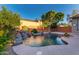 Lush backyard features a gorgeous pool with a stunning rock waterfall feature at 4565 N Point Ridge Rd, Buckeye, AZ 85396