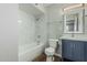 Bathroom showcasing tub with marble-look tile surround, a toilet, and vanity with navy cabinets at 5022 W Pierson St, Phoenix, AZ 85031