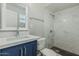 Bathroom featuring shower with marble-look tile surround and vanity with navy cabinets at 5022 W Pierson St, Phoenix, AZ 85031