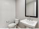 Powder room featuring toilet, pedestal sink, and modern square mirror at 5840 E Covey Ln, Phoenix, AZ 85054