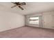 Bright living room showcasing carpet flooring, a ceiling fan, large windows and neutral paint at 6027 E Ellis St, Mesa, AZ 85204