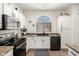 Well-lit kitchen features black appliances, white cabinetry, a sink under an arched window, and a stylish backsplash at 6505 S 15Th Dr, Phoenix, AZ 85041