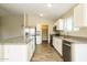 Bright kitchen with stainless steel appliances, granite countertops, white cabinets, and ample storage space at 6875 W Townley Ave, Peoria, AZ 85345