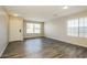 A well-lit living room featuring laminate flooring, a front door, and large windows at 6875 W Townley Ave, Peoria, AZ 85345