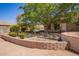 Expansive backyard featuring mature trees, a brick retaining wall, and a secluded seating area at 9658 W Golddust Dr, Queen Creek, AZ 85144
