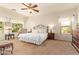 Spacious main bedroom boasts a ceiling fan, two windows, and neutral carpet at 9658 W Golddust Dr, Queen Creek, AZ 85144