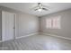 Neutral bedroom with tile floor, white door, shuttered window and ceiling fan at 12801 W Sweetwater Ave, El Mirage, AZ 85335