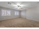 Large bedroom featuring neutral walls, carpet, a ceiling fan, and white shuttered windows at 12801 W Sweetwater Ave, El Mirage, AZ 85335