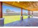 Covered patio highlighting stone flooring, wooden beam supports, and a view of the backyard at 12801 W Sweetwater Ave, El Mirage, AZ 85335