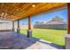 Covered patio showcasing stone flooring, wooden beam supports, and a view of the backyard at 12801 W Sweetwater Ave, El Mirage, AZ 85335