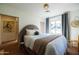 Cozy bedroom with large bed, decorative pillows, window with gray curtains, and tiled floors at 1309 W Lynwood St, Phoenix, AZ 85007