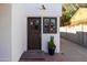 Charming entrance with a dark wood door, accent window, potted succulent, and outdoor lighting fixture at 1309 W Lynwood St, Phoenix, AZ 85007
