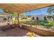 Charming backyard with a covered patio, green grass, and mature trees at 131 N Higley Rd # 41, Mesa, AZ 85205