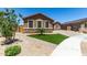 Well-maintained single-story home featuring stone accents, desert landscaping, and a charming green lawn at 15740 W Washington St, Goodyear, AZ 85338