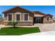Inviting single-story home featuring a landscaped front yard with desert accents and a brick paved driveway at 15740 W Washington St, Goodyear, AZ 85338