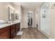 Well-lit main bathroom features double sinks, wood cabinets and glass enclosed shower at 15740 W Washington St, Goodyear, AZ 85338