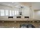 Bright, open living room features a stone fireplace, ceiling fan, and multiple windows for ample natural light at 16386 W Papago St, Goodyear, AZ 85338