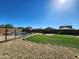 Backyard featuring green grass, desert rock border, fire pit and neighborhood views under a clear blue sky at 19324 N Del Mar Ave, Maricopa, AZ 85138