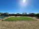 Backyard featuring green grass, desert rock border, fire pit and neighborhood views under a clear blue sky at 19324 N Del Mar Ave, Maricopa, AZ 85138