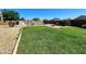 Backyard featuring green grass, desert rock border, fire pit and neighborhood views under a clear blue sky at 19324 N Del Mar Ave, Maricopa, AZ 85138