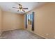 A simple, carpeted bedroom features a ceiling fan and a window with curtains at 19324 N Del Mar Ave, Maricopa, AZ 85138
