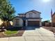 Two-story home featuring a two-car garage, neutral color scheme, manicured yard with tree, rock details and American flag at 19324 N Del Mar Ave, Maricopa, AZ 85138