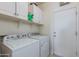 Functional laundry room with white appliances and shelving for storage at 19324 N Del Mar Ave, Maricopa, AZ 85138