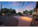 Well-maintained backyard featuring a custom stone fire pit, mature landscaping and outdoor lighting at 19334 W Pasadena Ave, Litchfield Park, AZ 85340