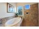 Luxurious bathroom with a soaking tub, shower, and large window for natural light at 19334 W Pasadena Ave, Litchfield Park, AZ 85340