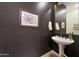 Elegant powder room with a pedestal sink, decorative artwork and dark wall at 19334 W Pasadena Ave, Litchfield Park, AZ 85340