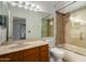 Well-lit bathroom with vanity, mirror, and a bathtub with glass door at 19833 N 47Th Ln, Glendale, AZ 85308