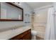 Bathroom showcasing a vanity with granite countertop, mirror, glass shelving, and shower-tub combo at 19833 N 47Th Ln, Glendale, AZ 85308
